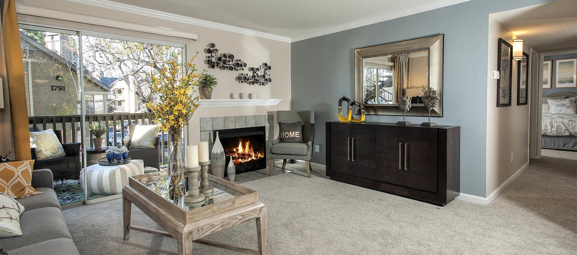 Living room in an apartment with a fireplace, balcony access, and modern furnishings.
