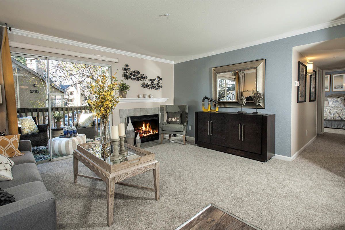 Living room in an apartment with a fireplace, grey sofa, and sliding glass door to the balcony.