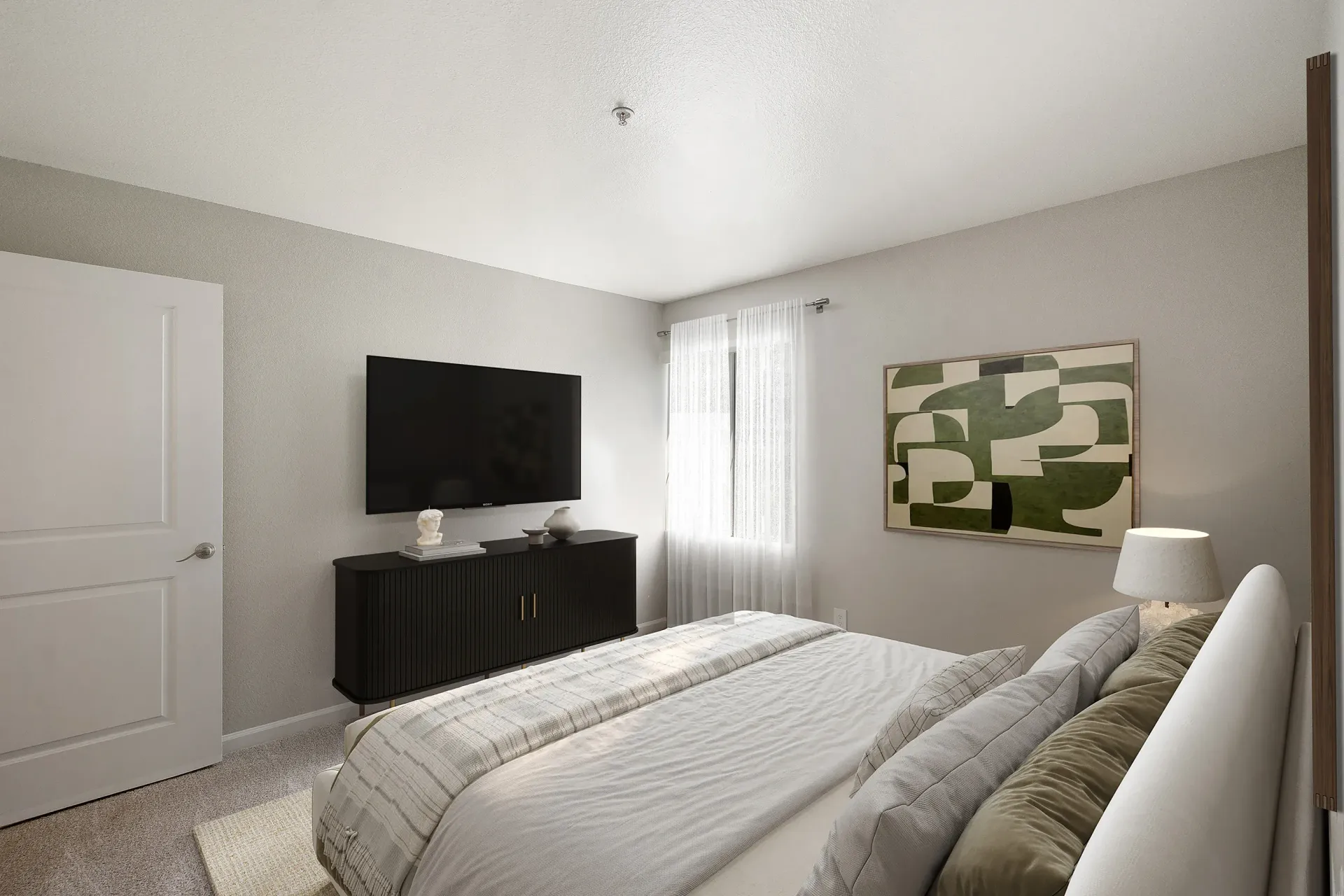 Bedroom with bed, TV on a low cabinet, window with sheer curtains and abstract wall art.