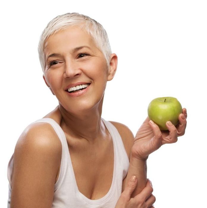 Una donna con capelli corti e una mela verde in mano