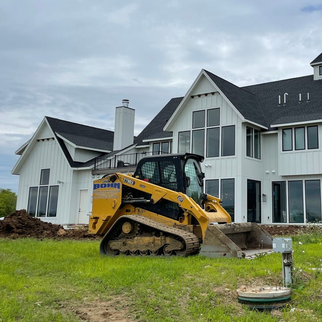 A bulldozer is sitting in front of a large white house.