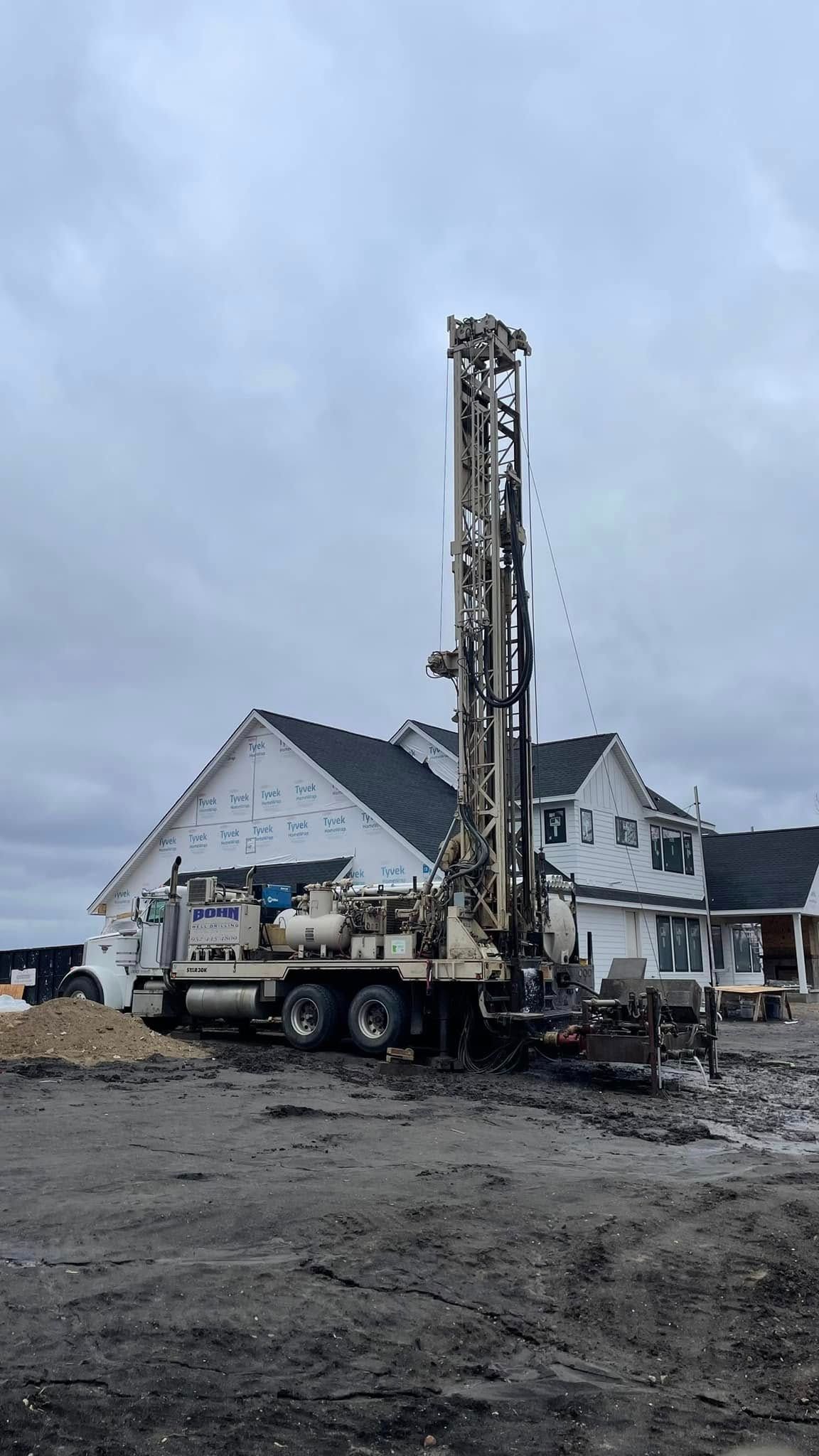 A large drilling rig is sitting in front of a house.