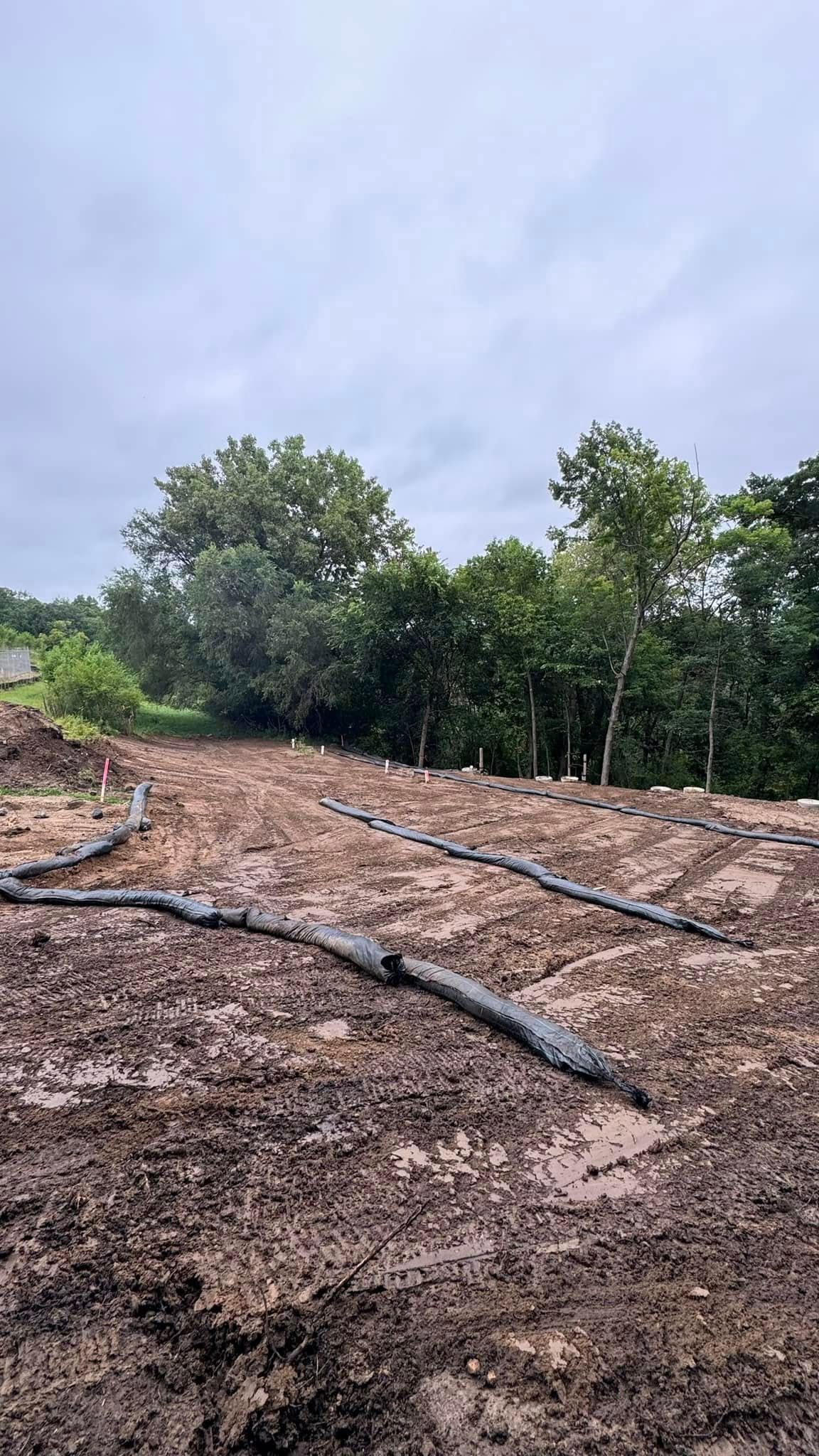 A muddy field with trees in the background on a cloudy day.
