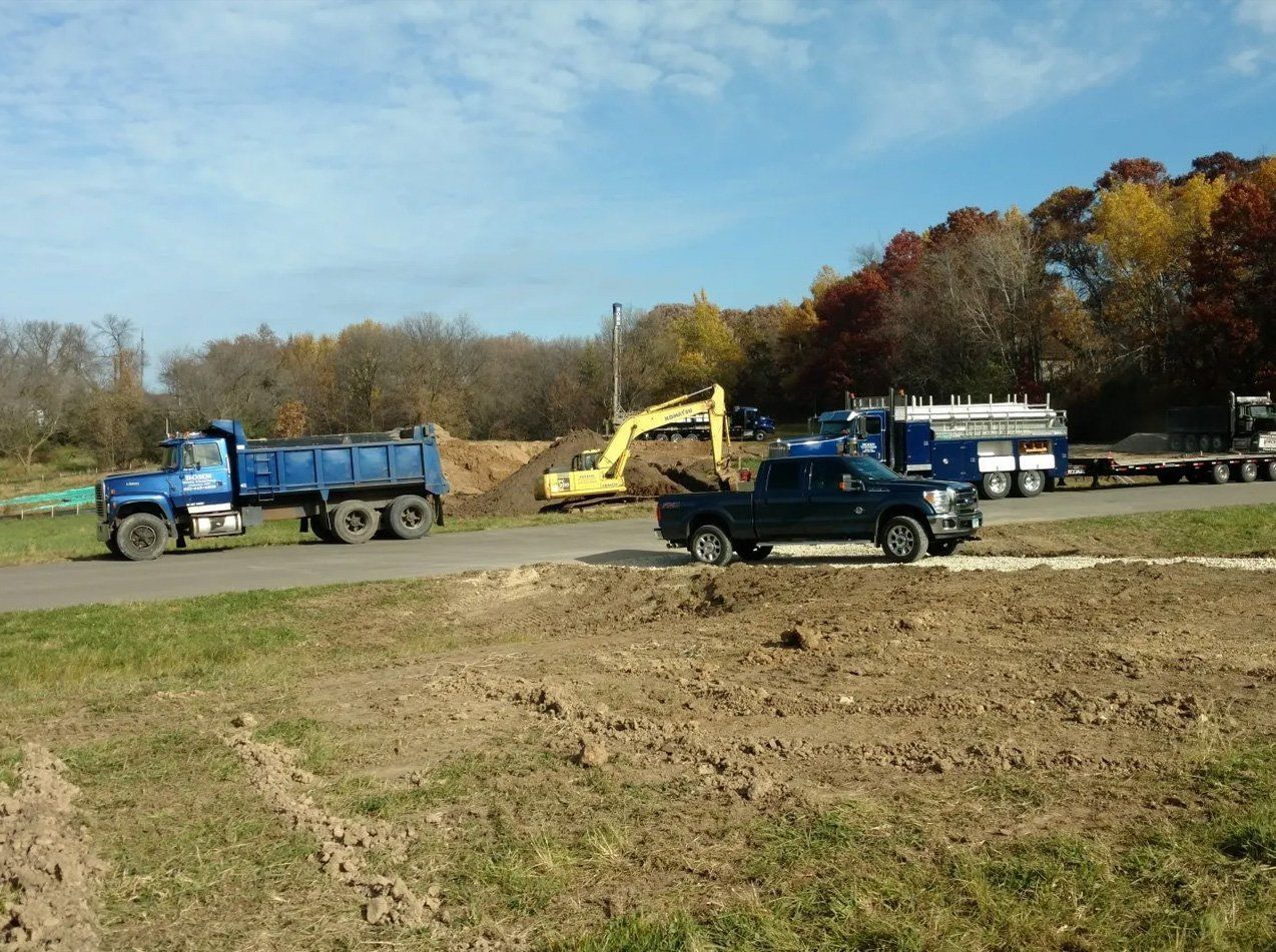 A dump truck and a truck are parked on the side of the road