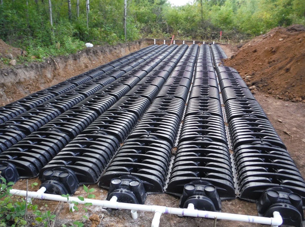 A row of black pipes are sitting in the dirt.