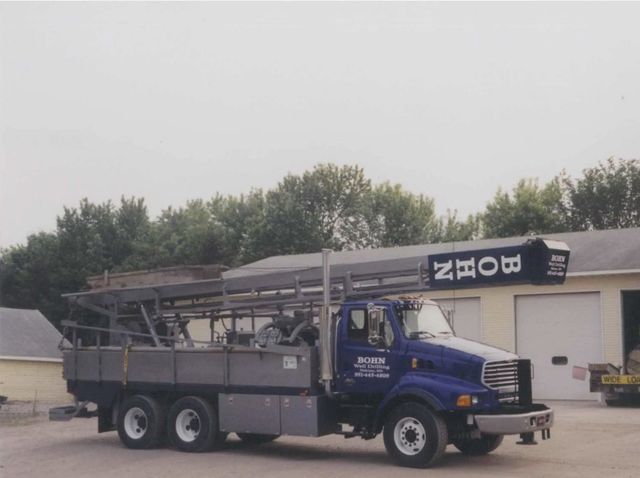 A Bohn truck is parked in front of a garage