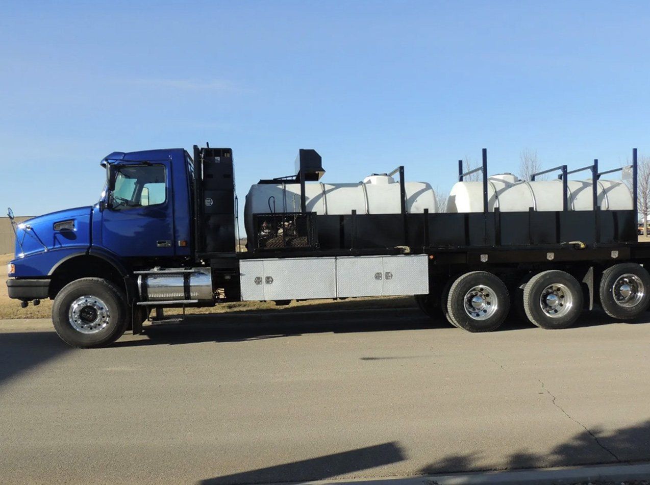 A blue truck with tanks on the back is parked on the side of the road.