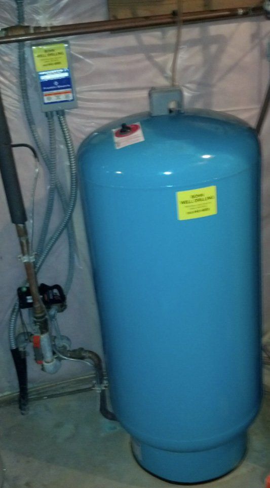 A blue water tank is sitting on the floor next to a wall.