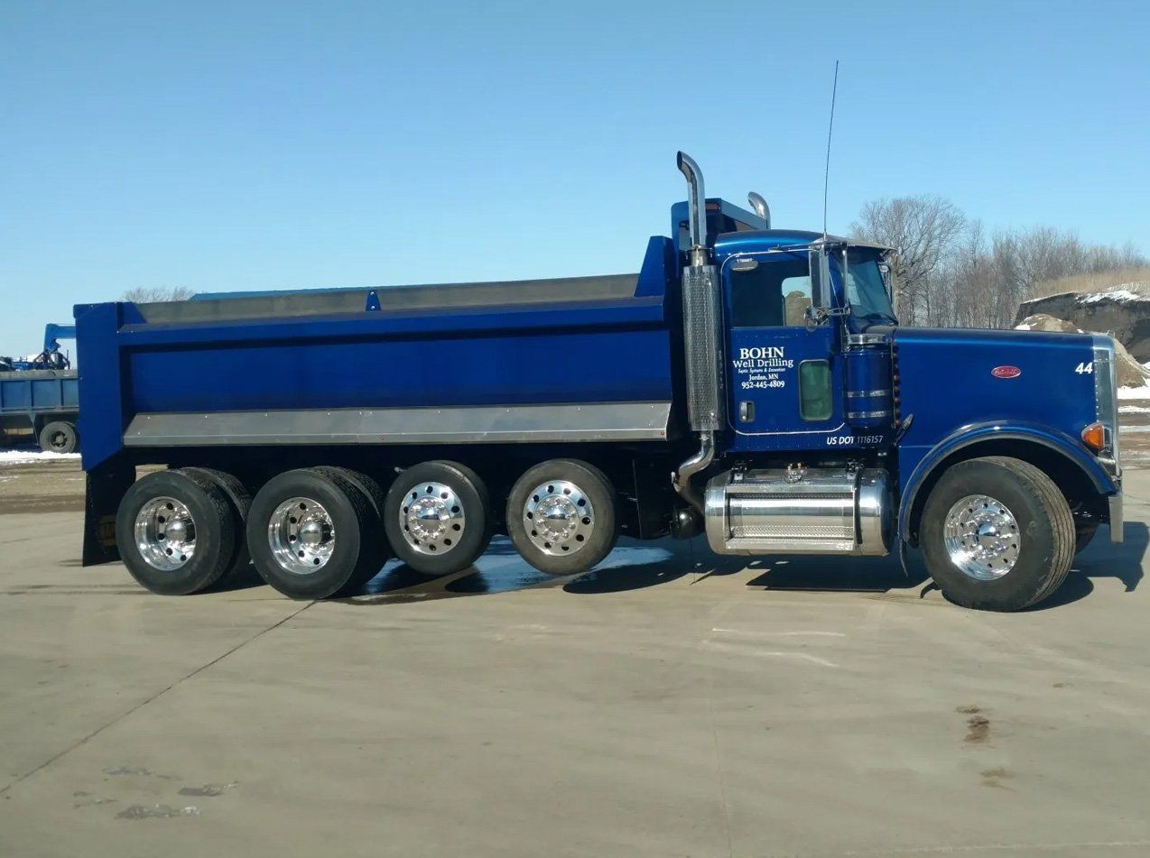 A blue dump truck is parked in a parking lot.