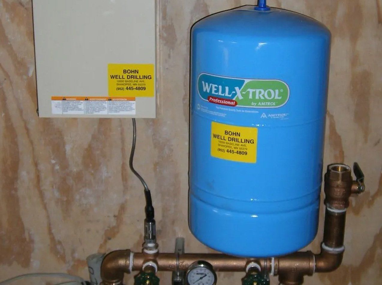 A blue well x-trol water tank sitting on top of copper pipes