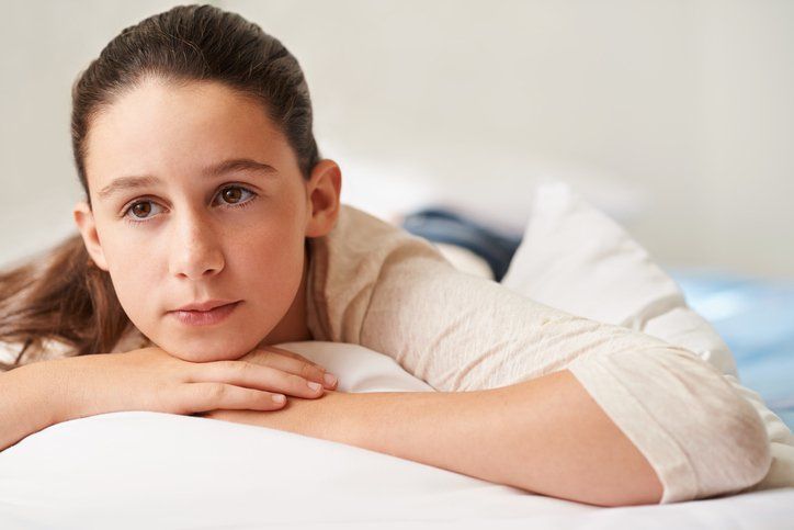 adolescente con sguardo triste appoggiata sul letto
