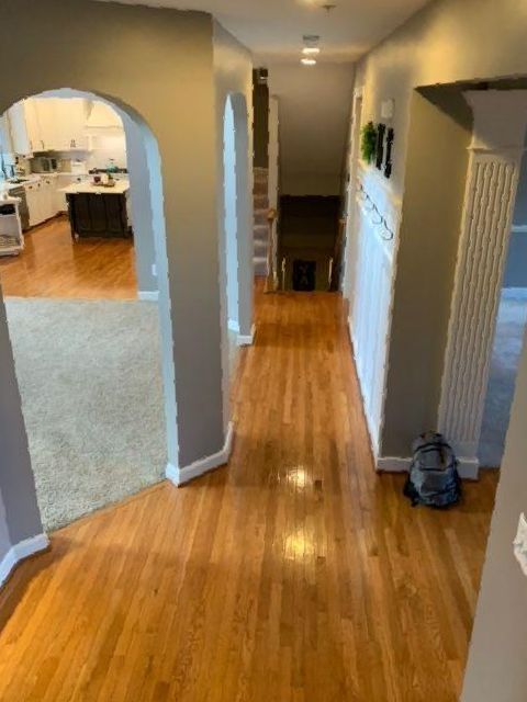A hallway with hardwood floors and a backpack on the floor