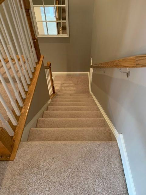 A staircase with a wooden railing and carpeted steps leading up to the second floor.