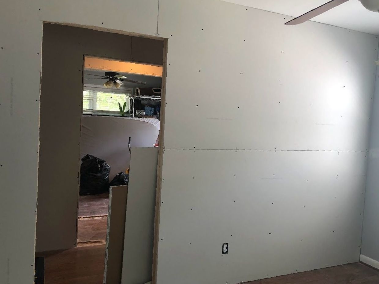 A room with a doorway leading to a kitchen and a ceiling fan.