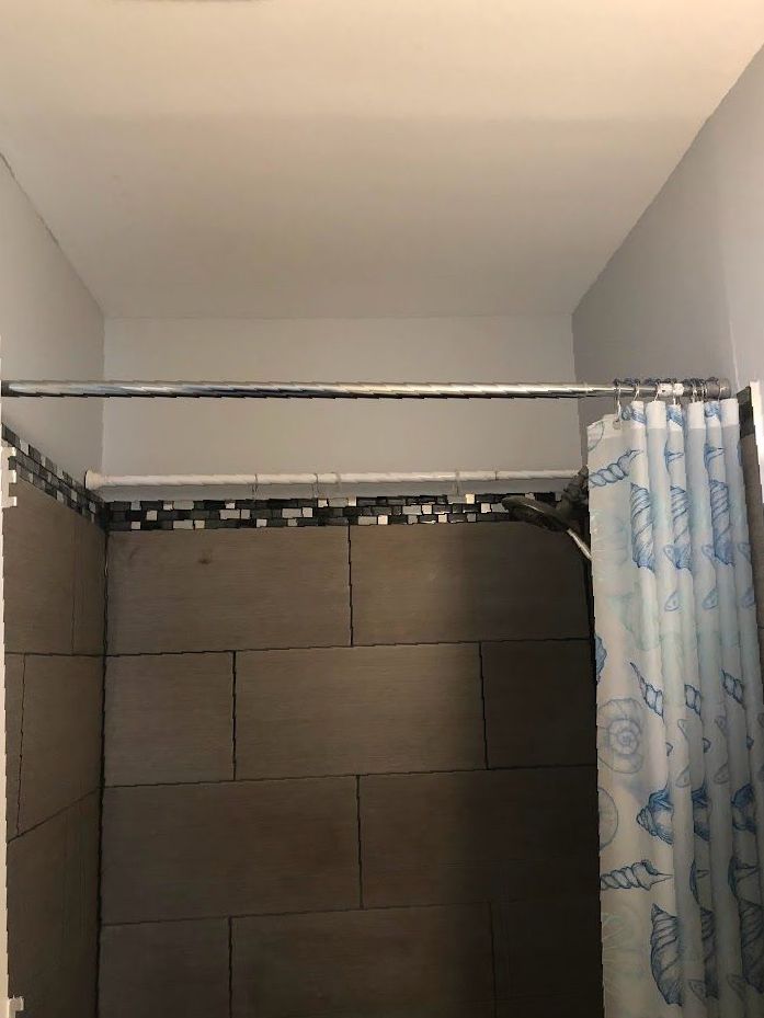 A bathroom with a shower curtain and a shower head.