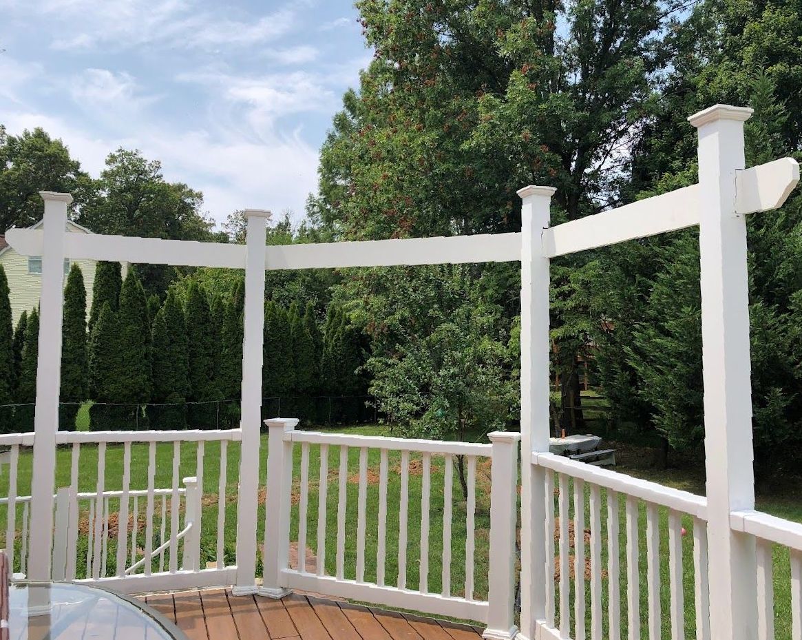 A deck with a white railing and trees in the background