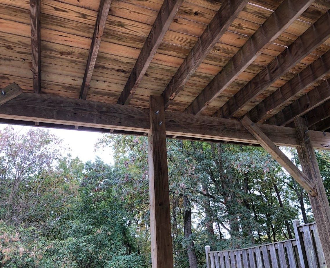 The ceiling of a wooden structure with trees in the background.
