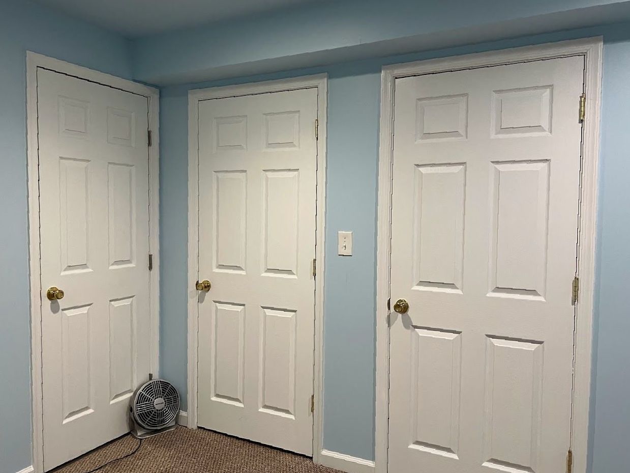 A room with three white doors and blue walls.