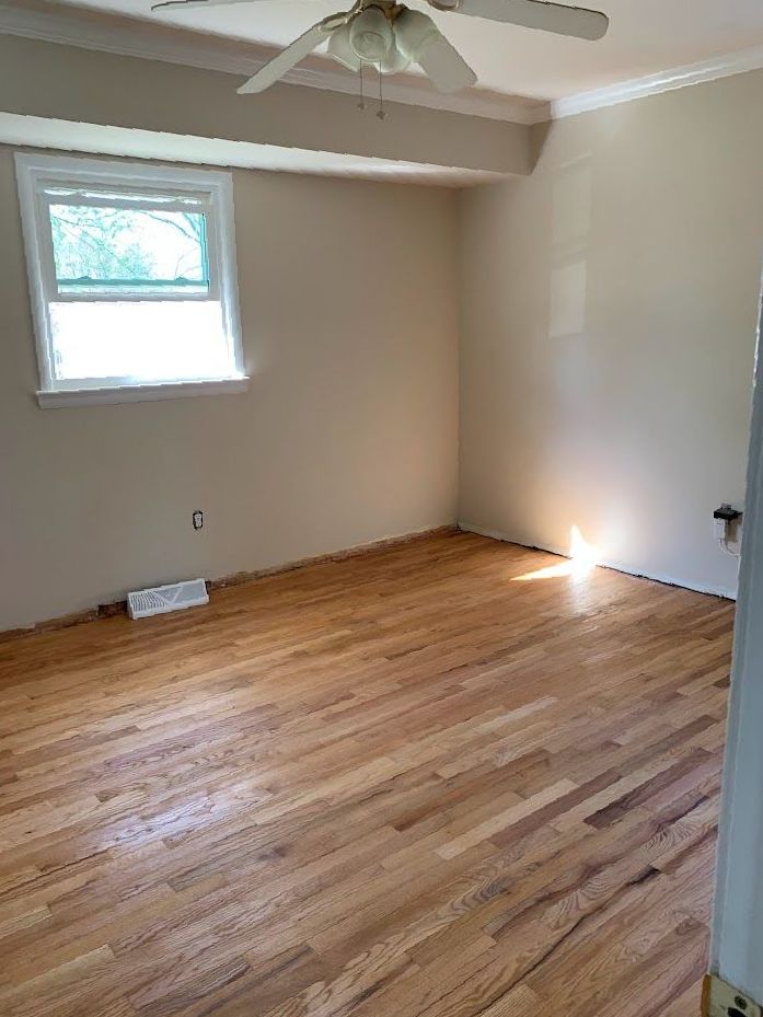 An empty room with hardwood floors and a ceiling fan.