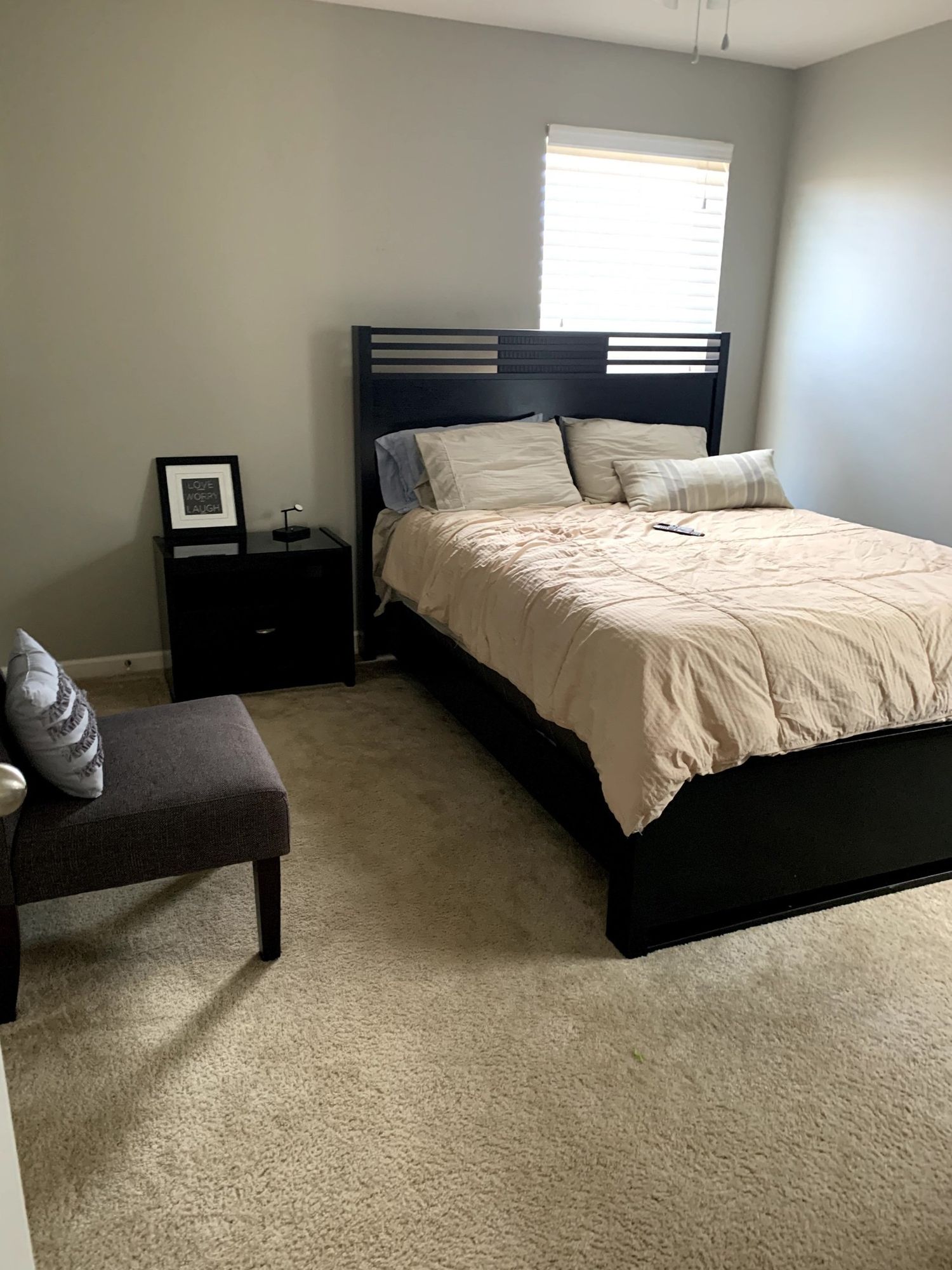 A bedroom with a bed , nightstand , chair and window.