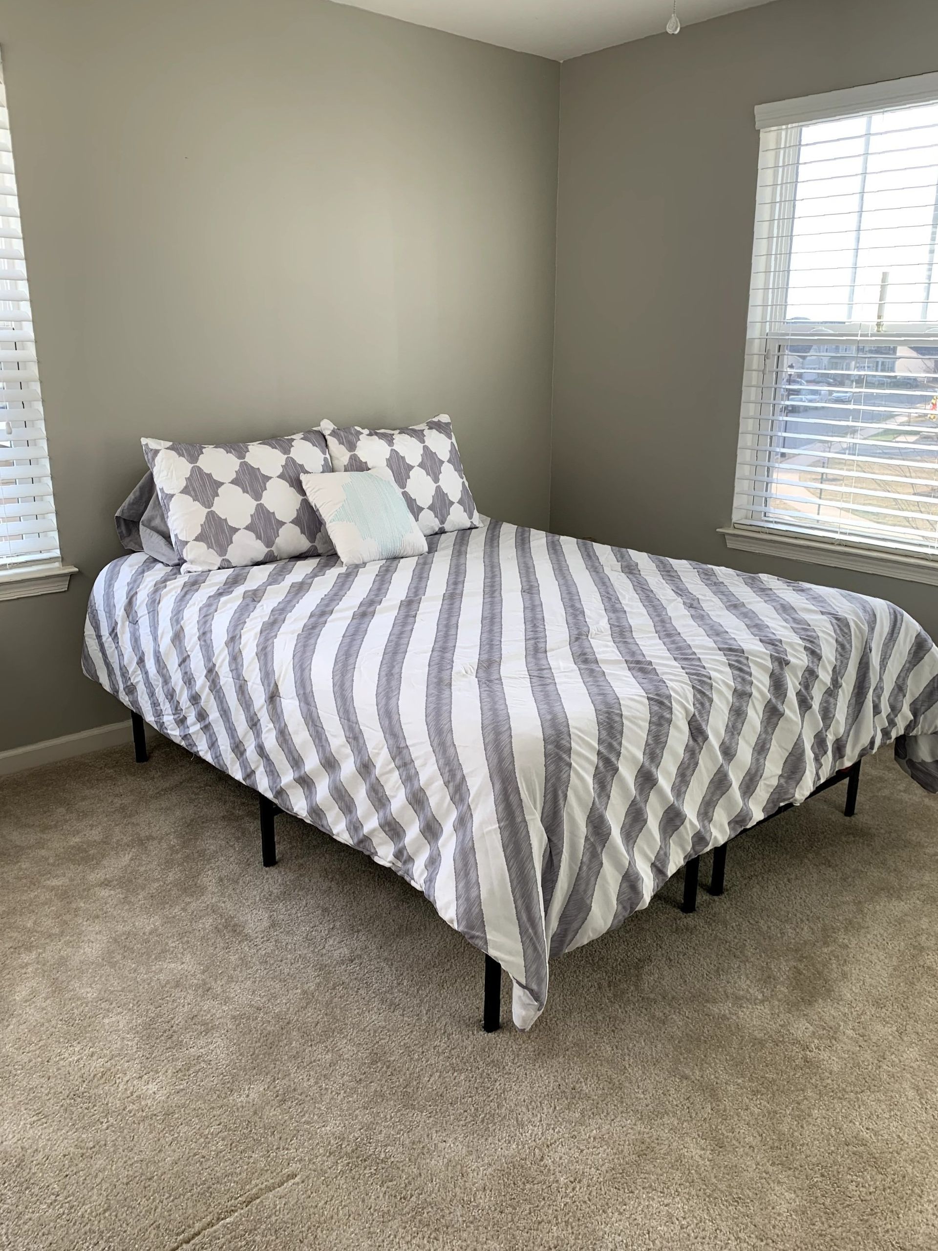 A bedroom with a bed , two windows and a striped comforter.