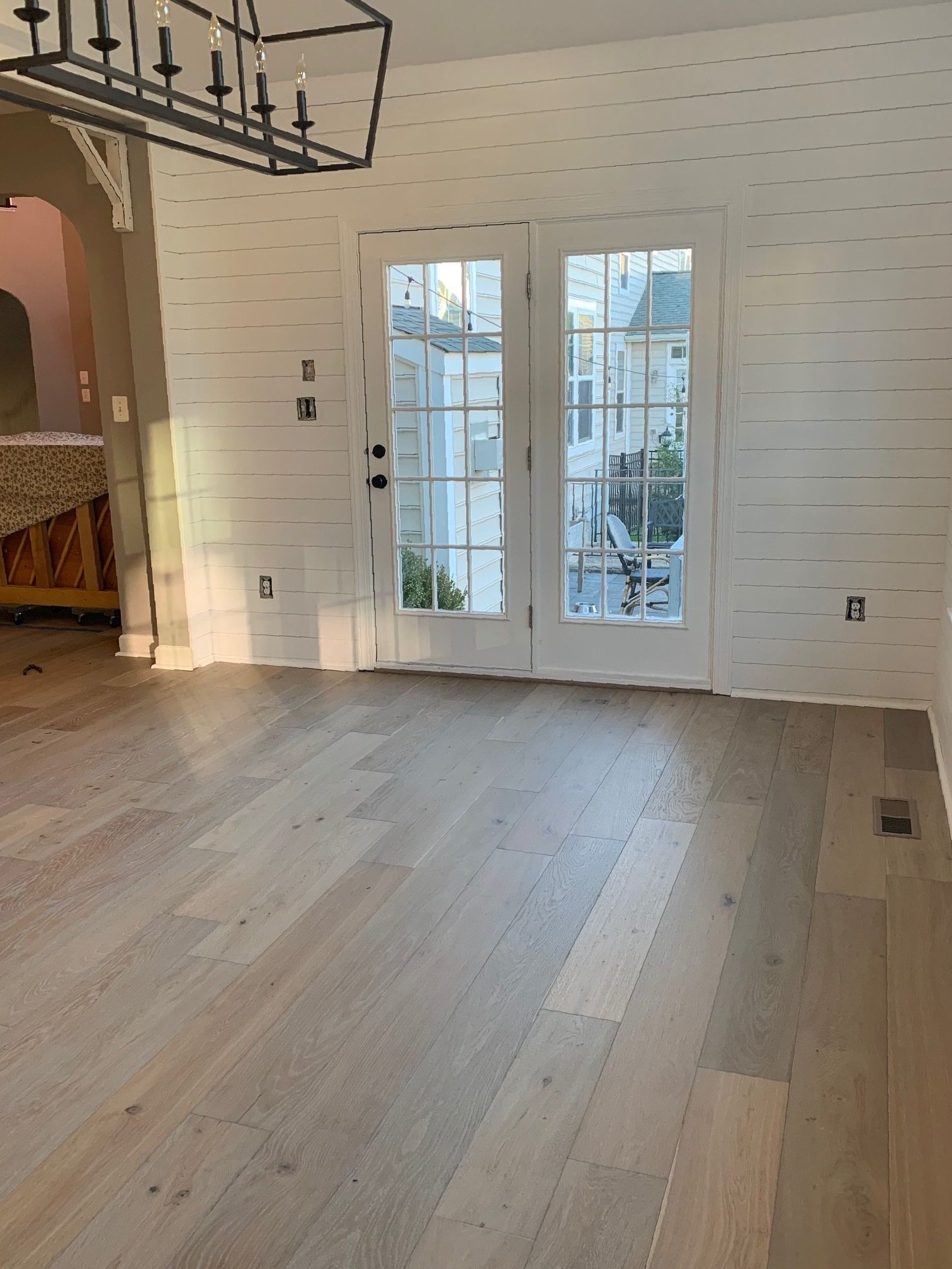 A living room with hardwood floors , white walls and french doors.