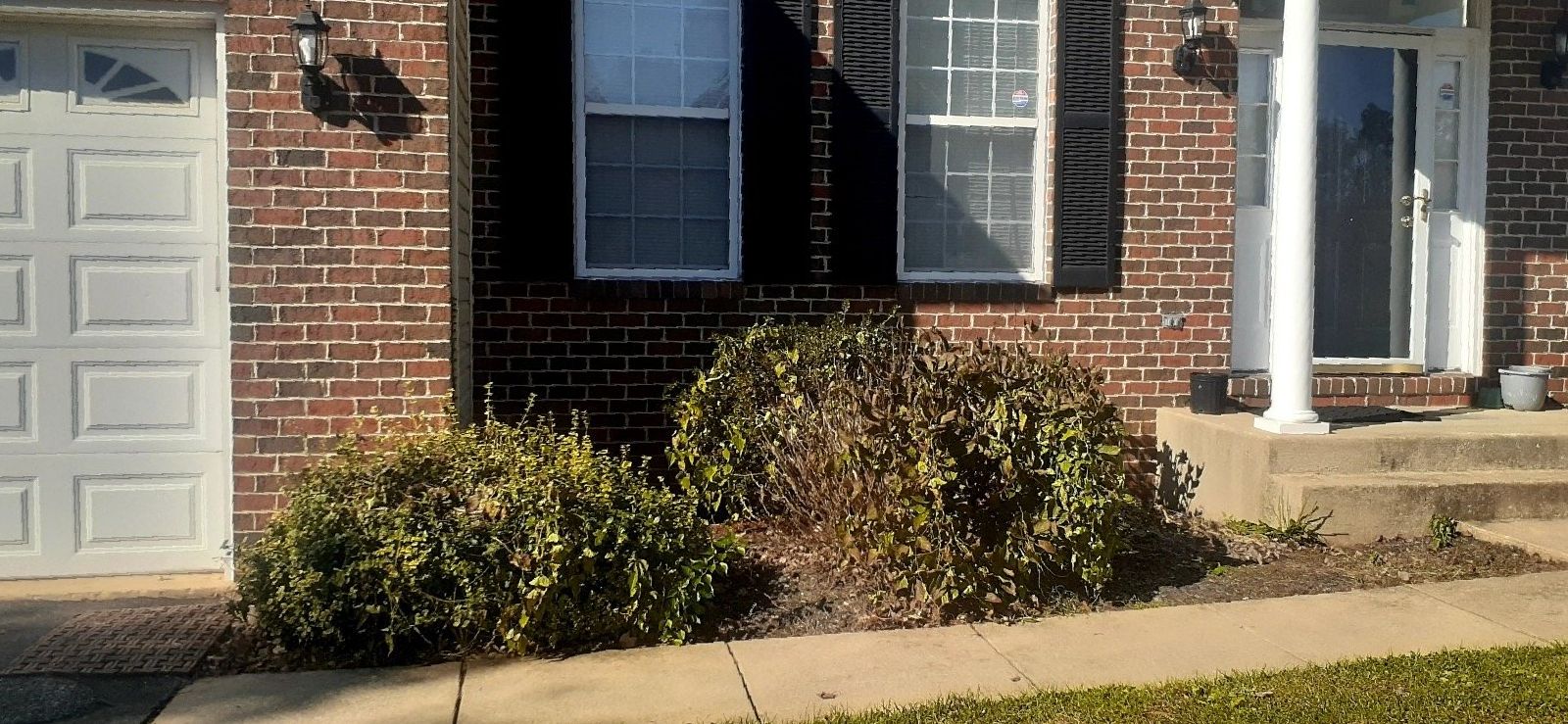 A brick house with a white garage door and black shutters