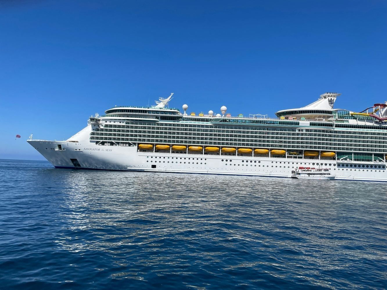 Large white cruise ship on blue water under a clear blue sky.