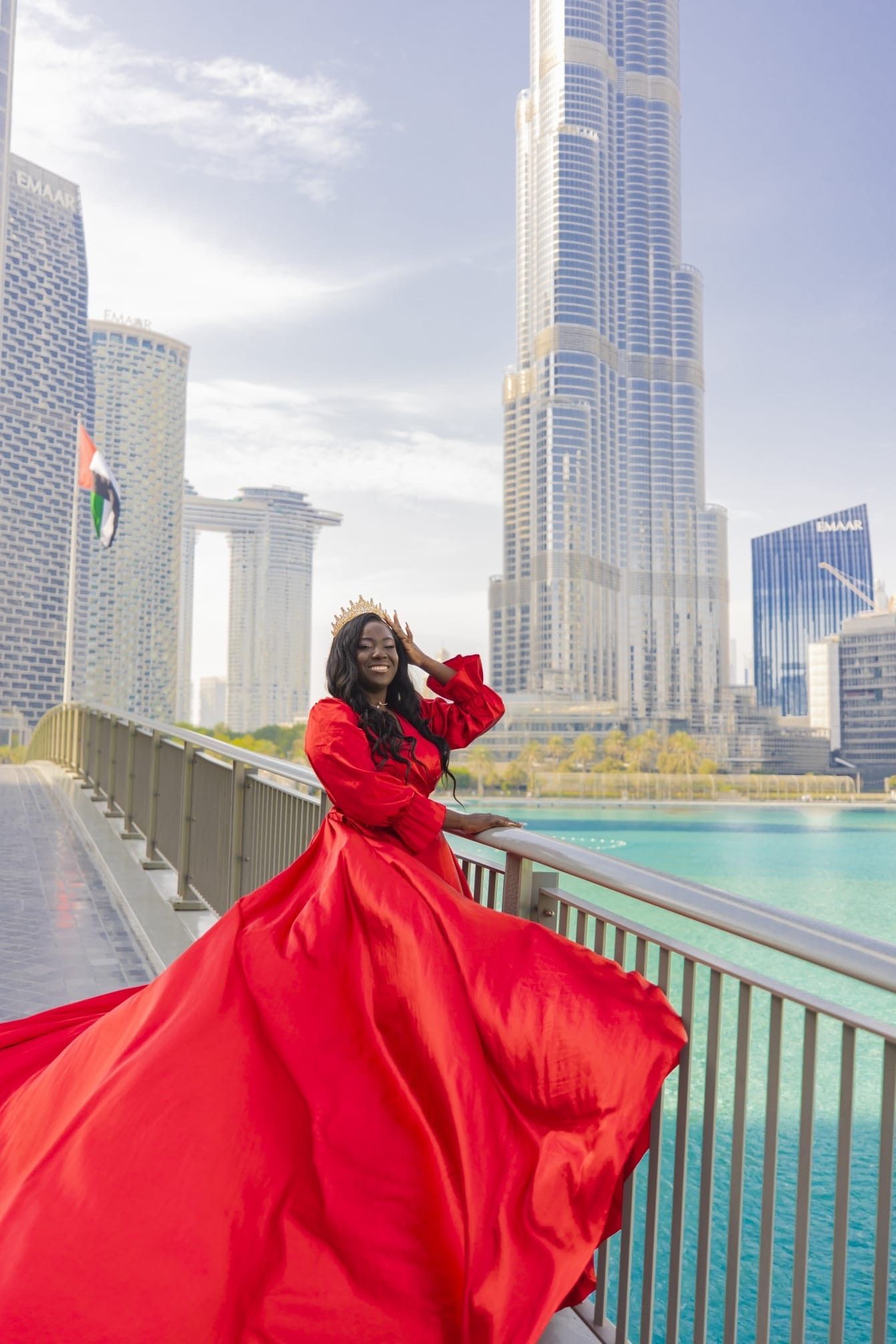 Woman in red dress posing near Burj Khalifa in Dubai.