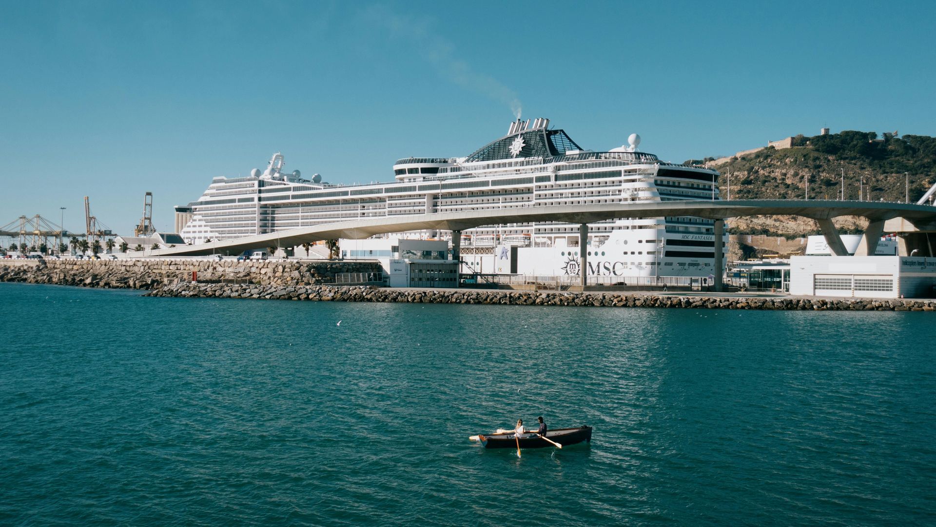 A large cruise ship traveling towards the horizon with clouds seen in the distance