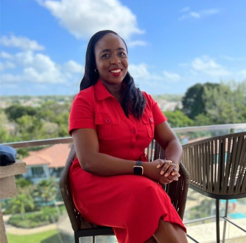 Two men in sunglasses smile at the camera, coastal scenery in background.