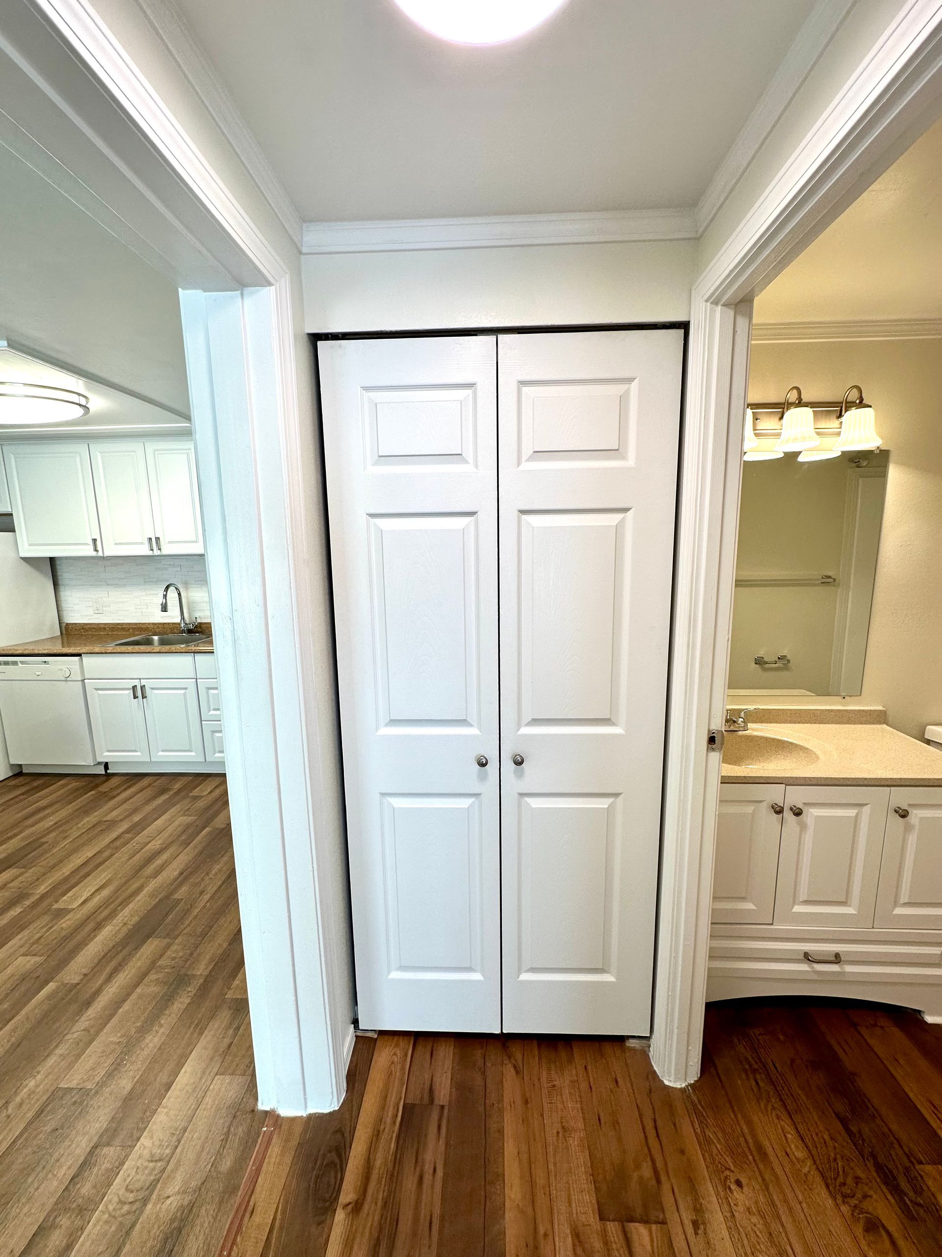 Hallway with white bi-fold closet doors; kitchen and bathroom on either side.