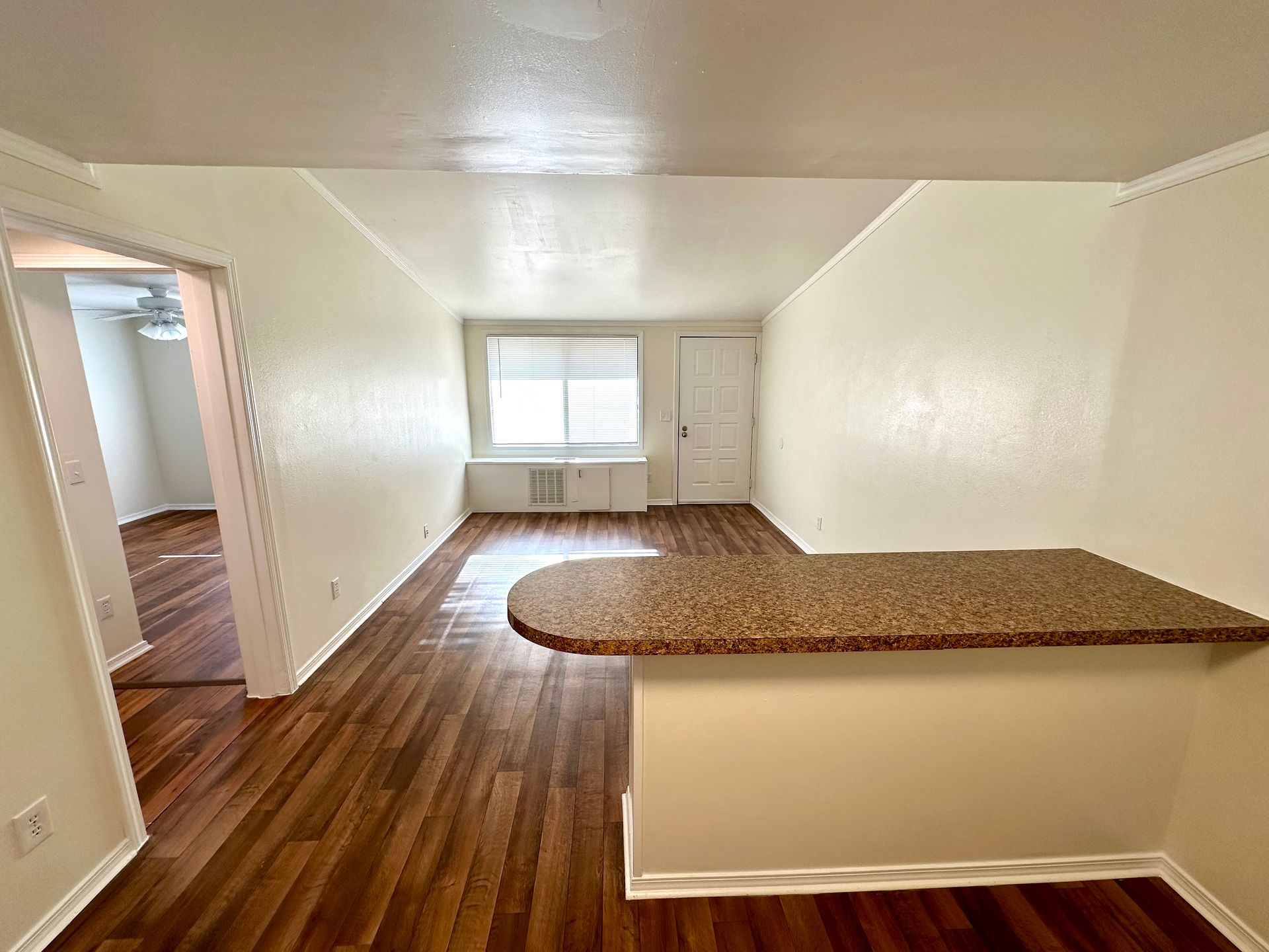 Apartment interior with faux wood flooring, a breakfast bar, and access to other rooms.