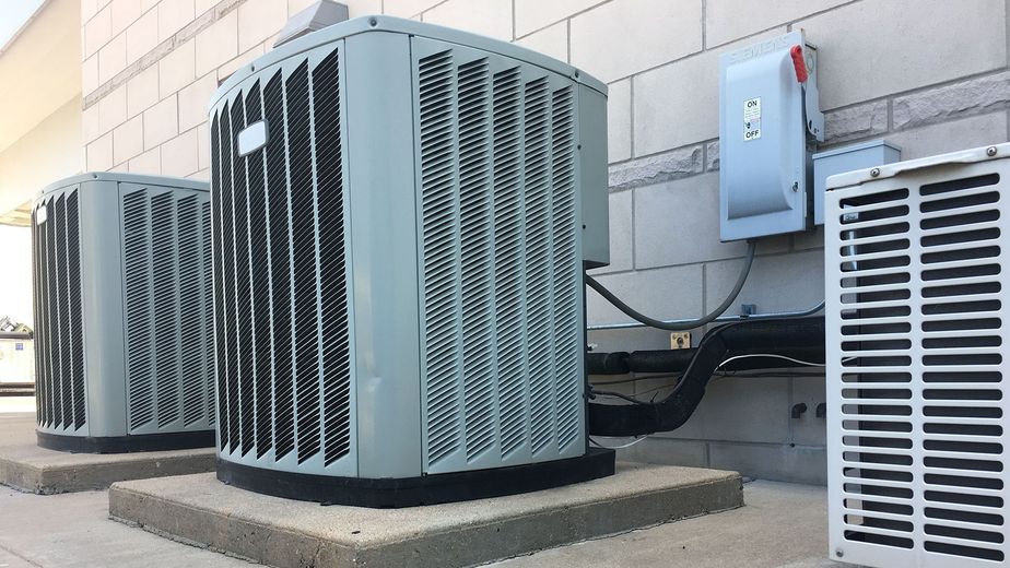 Two air conditioners are sitting on the side of a building.