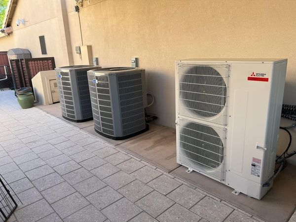 Two air conditioners are sitting on the side of a building.