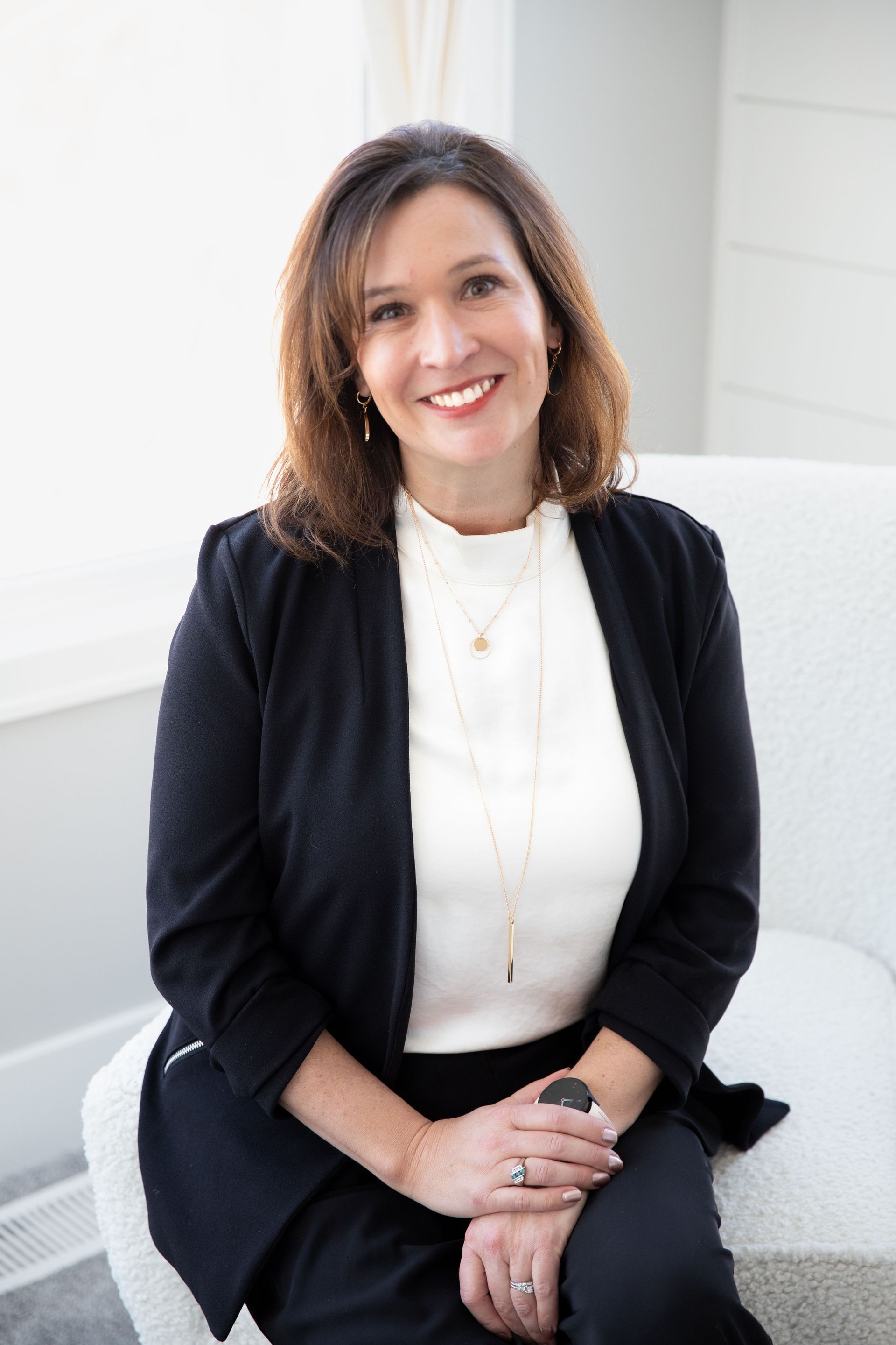 A woman is sitting at a desk with a laptop and a vase of flowers.
