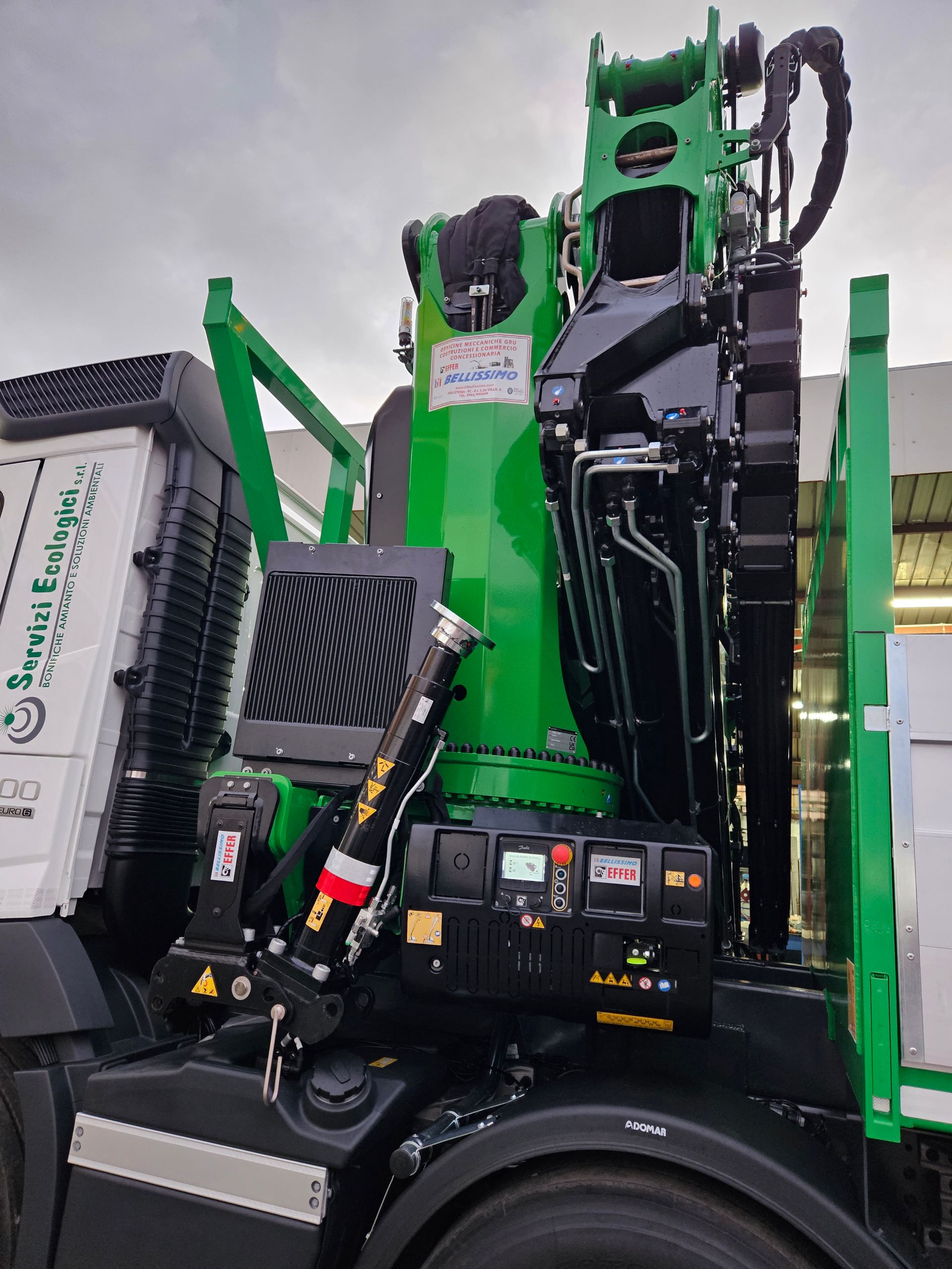 A green crane is attached to the back of a truck.