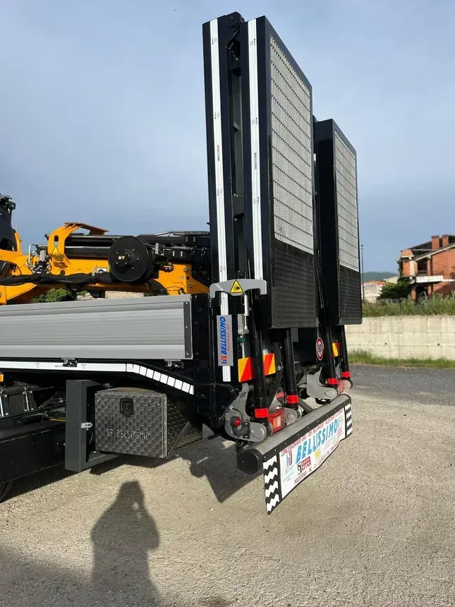 A truck with a crane on the back is parked on the side of the road.