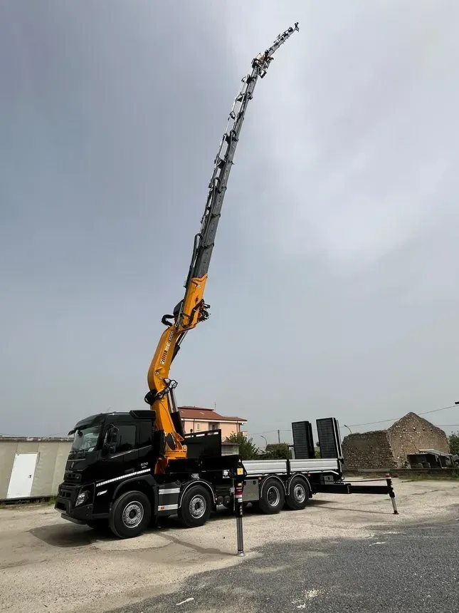 A truck with a crane attached to it is parked in a parking lot.