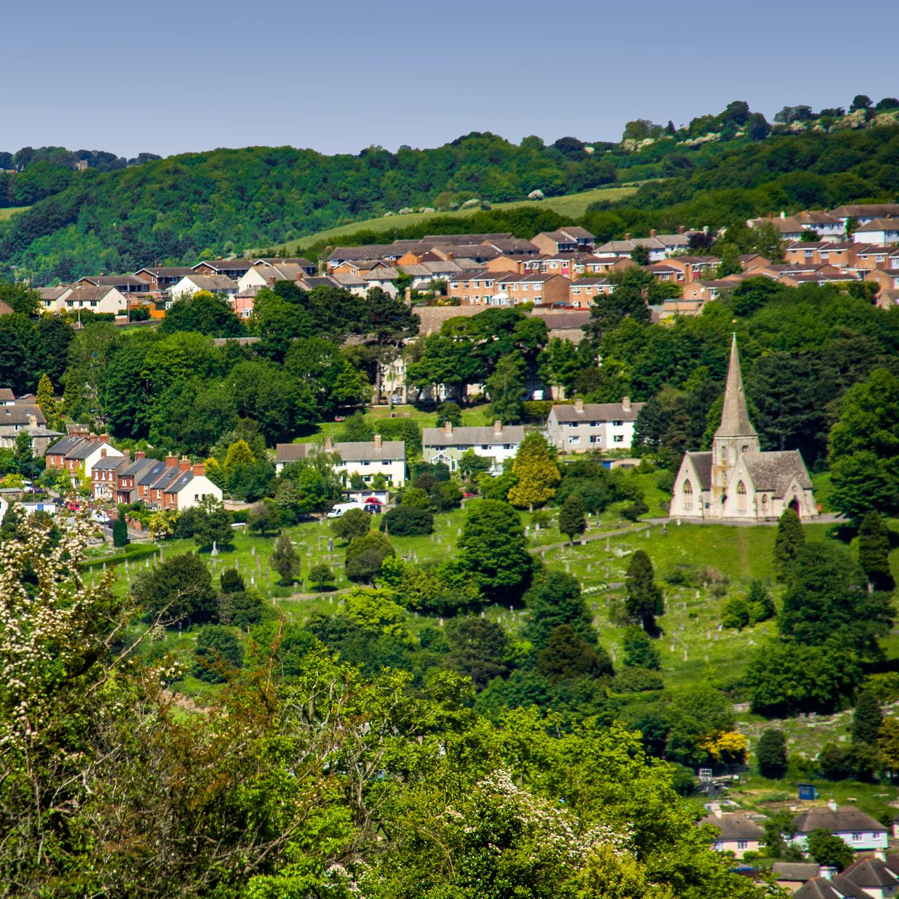 A view of a hillside with houses and a church in Stroud, Gloucestershire England, United Kingdom. The image shows a mix of property types both modern and Victorian.