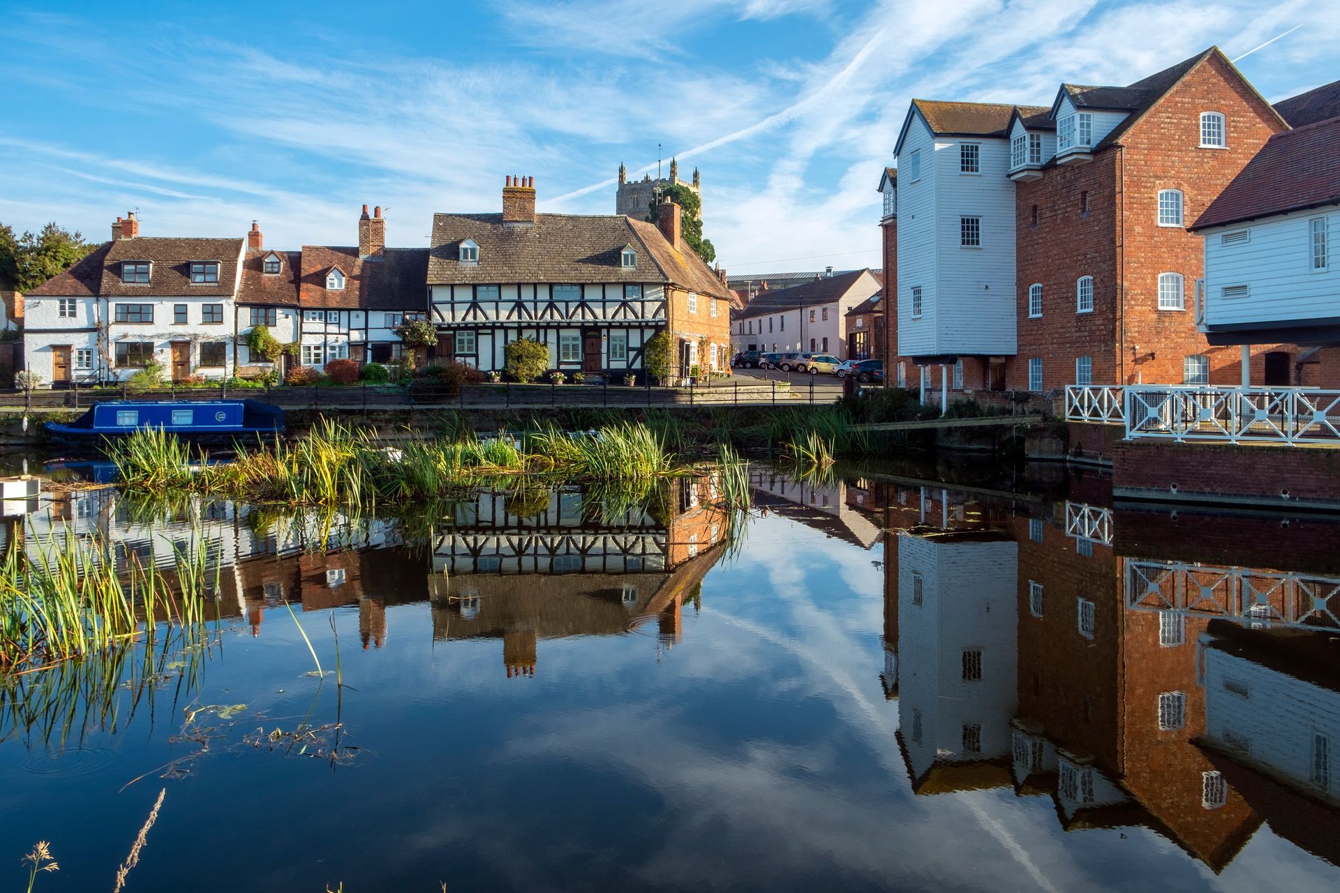 A picturesque group of idyllic historic 17th century cottages near Abbey Mill in the town of Tewkesbury, Gloucestershire, Severn Vale, United Kingdom with Tewkesbury Abbey in the background.