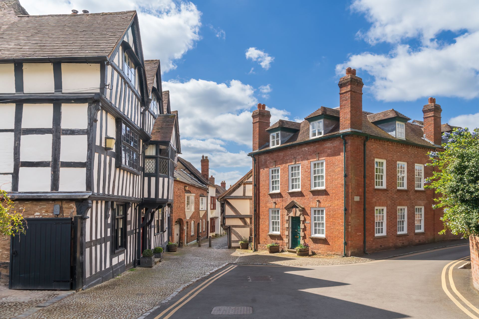 View of a typical beautiful street in Ledbury, Herefordshire, England with a mix of Tudor Georgian and Victorian properties on cobbled streets.