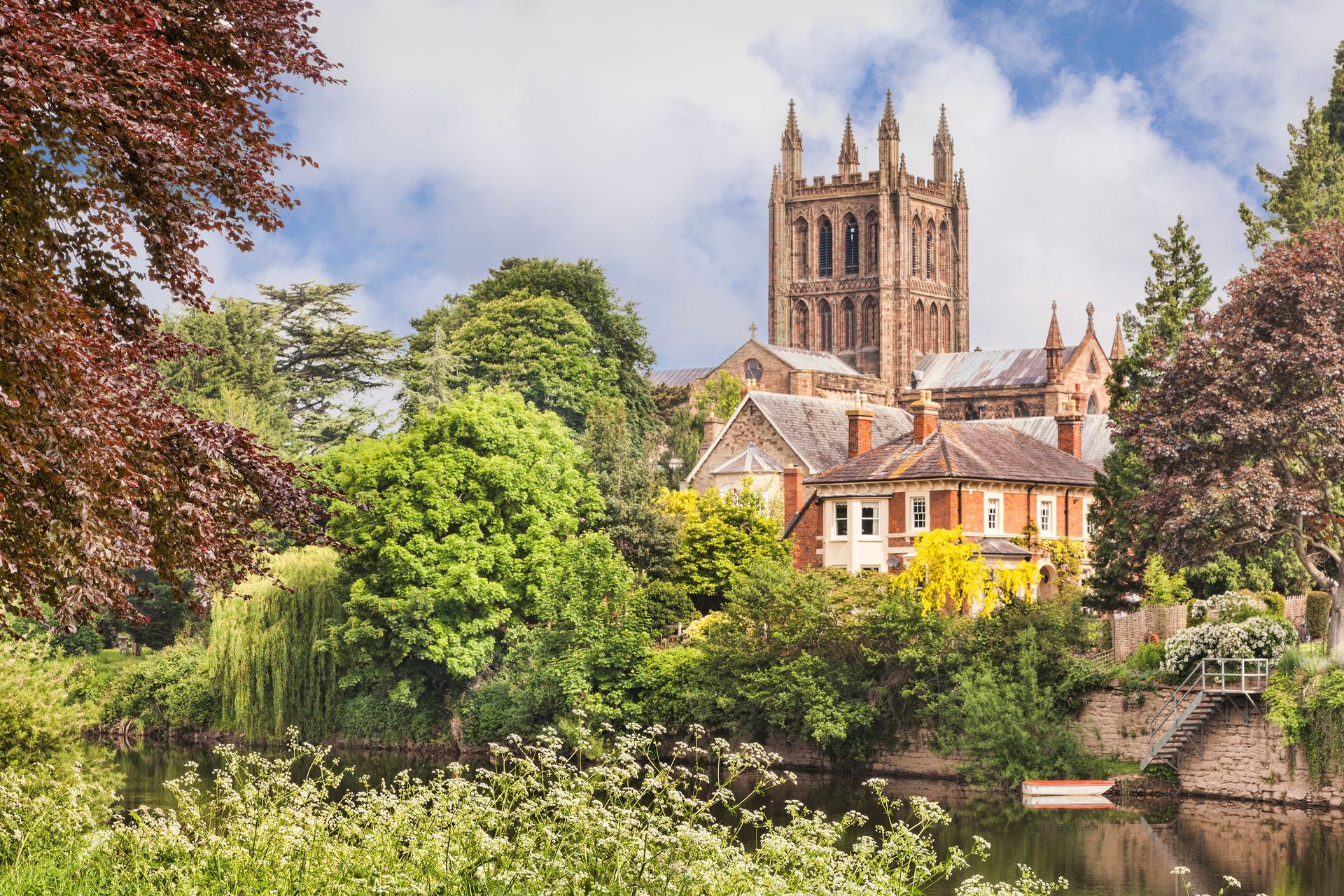 A stunning view across the River Wye, Herefordshire towards the tower of Hereford Cathedral in the background.  Georgian period town houses are situated between the lush trees and cathedral.