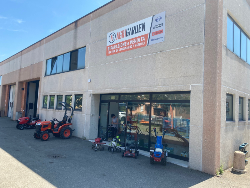 Esterno del negozio Mr. Garden, esposizione di attrezzature per esterni. L'edificio è di colore chiaro. Giornata di sole.