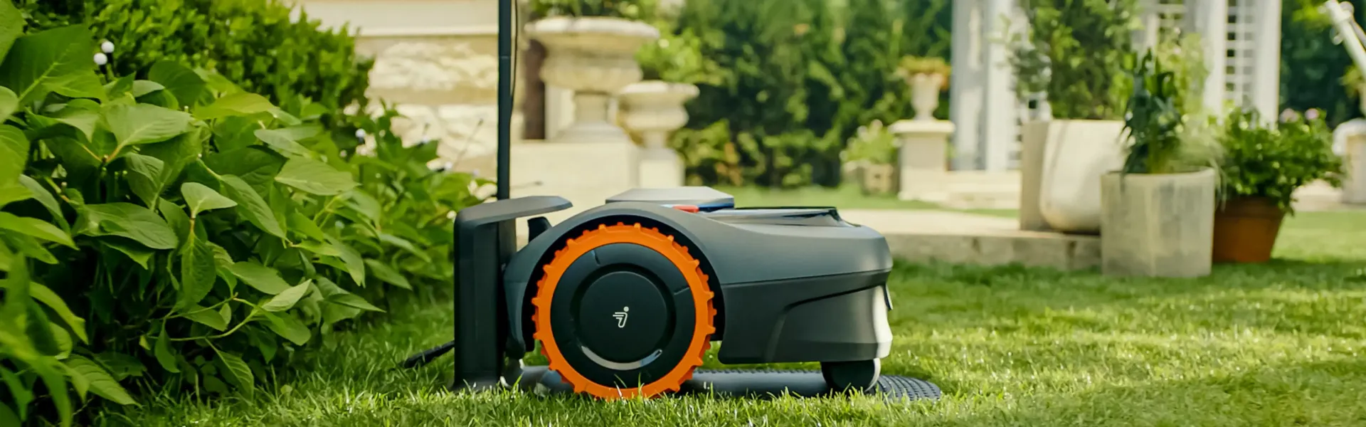 Un rasaerba robotizzato su un prato verde con lo sfondo sfocato di un giardino.