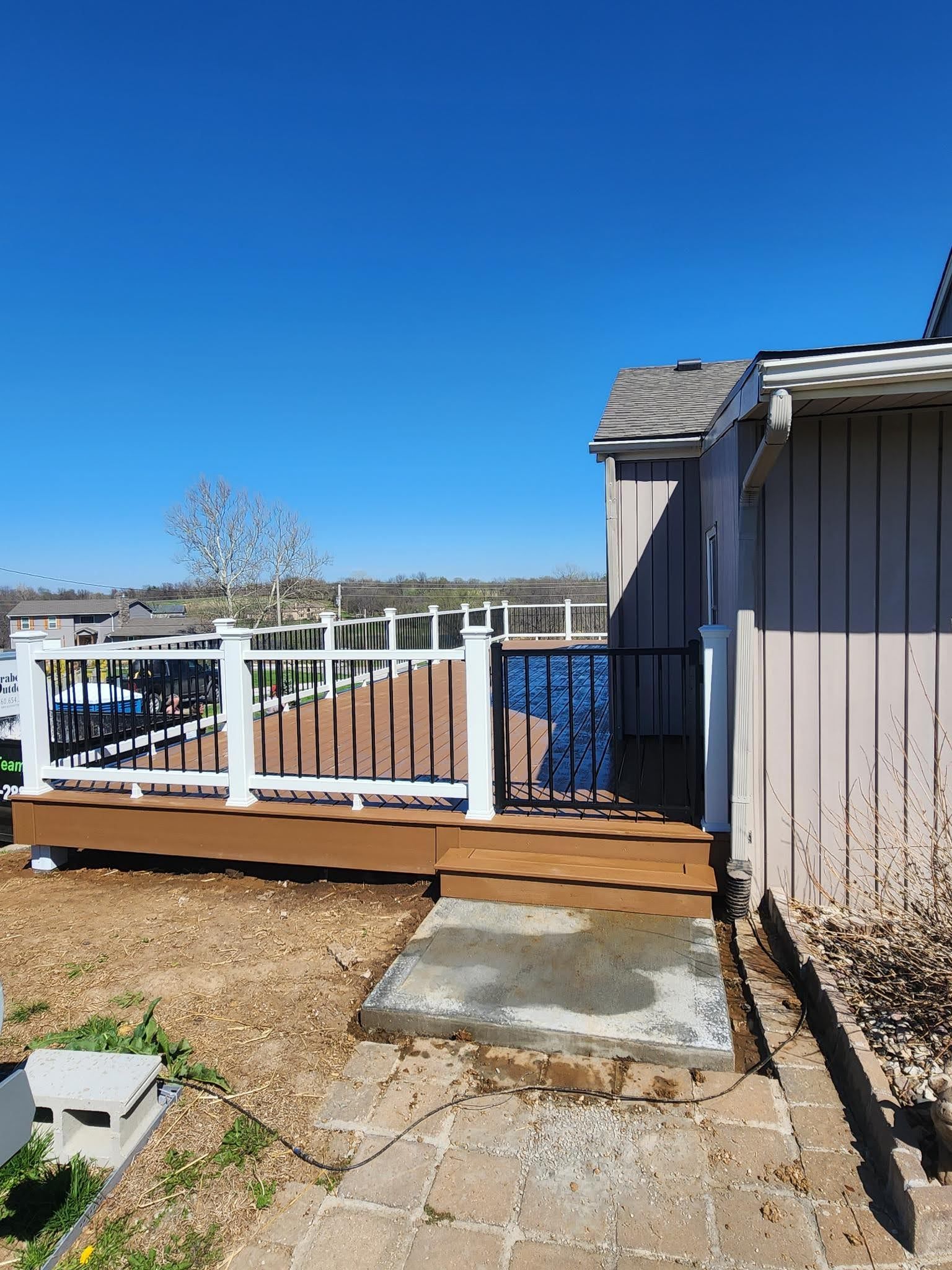 A wooden deck with a white railing is next to a house.