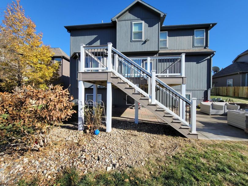 The back of a house with a deck and stairs leading up to it.