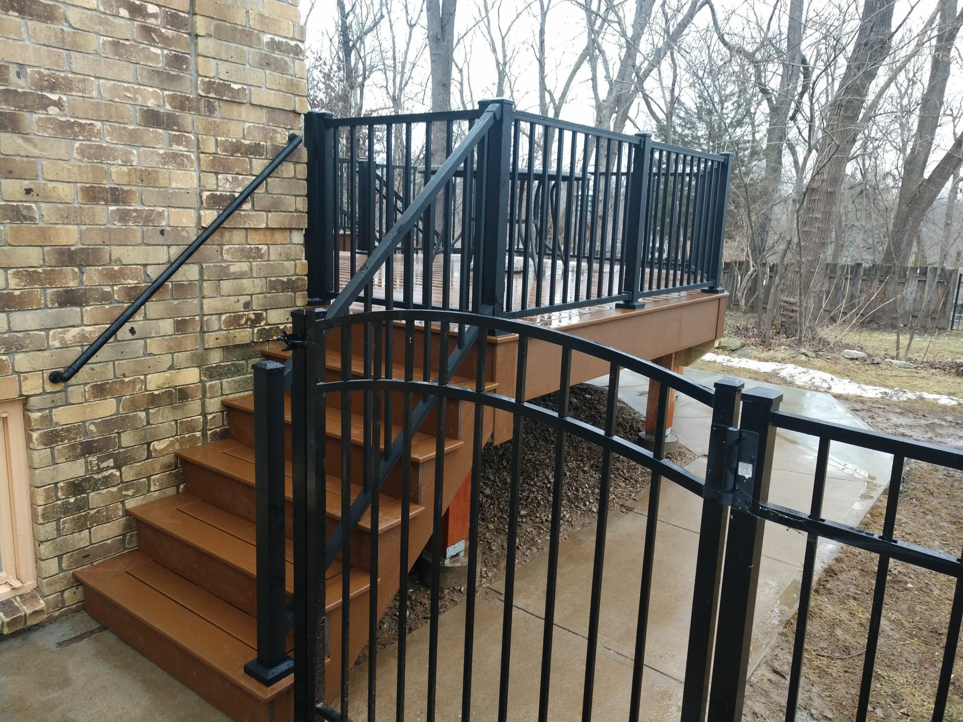 A wooden deck with stairs and a black fence