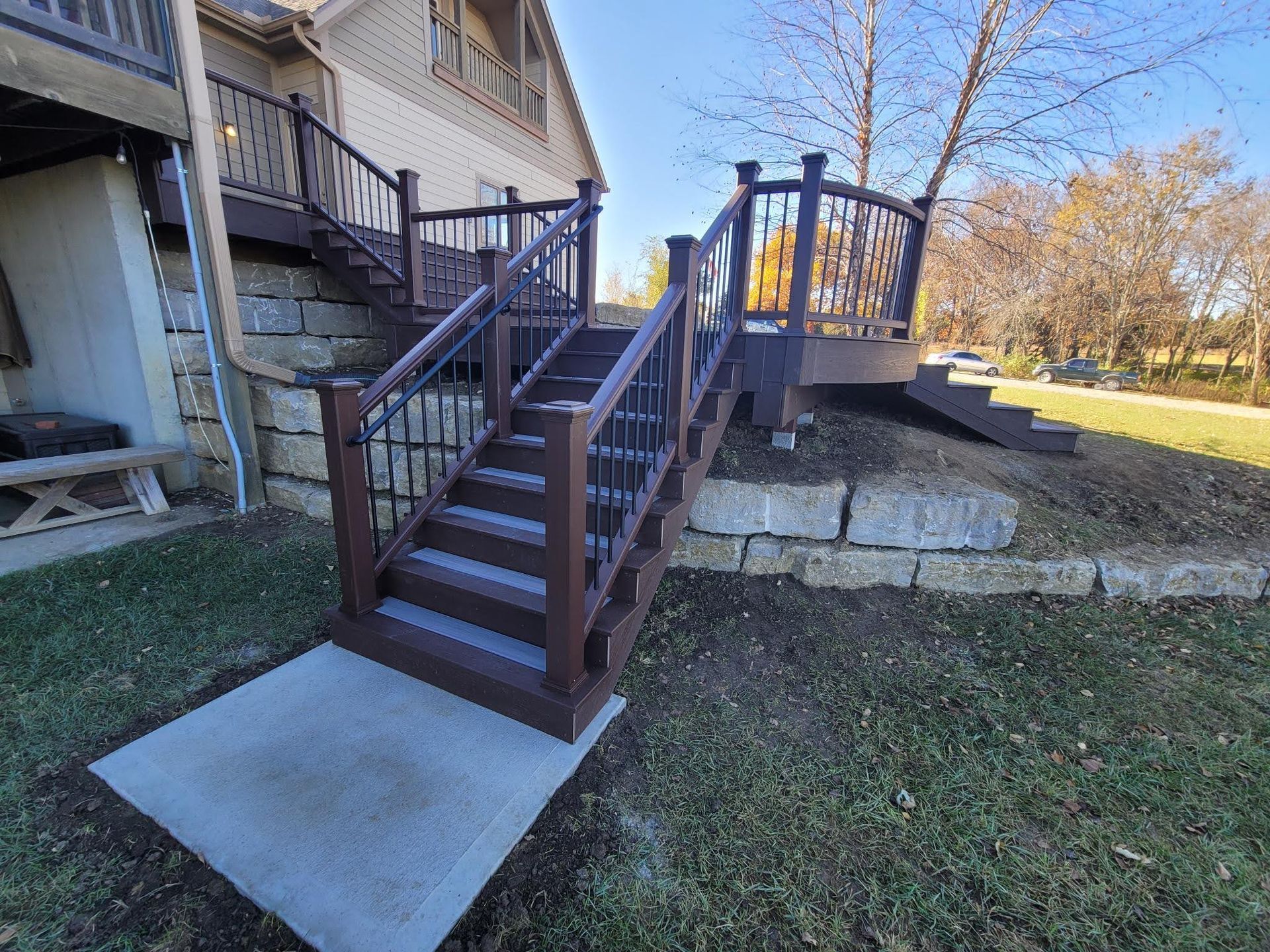 A wooden deck with stairs leading up to it in front of a house.