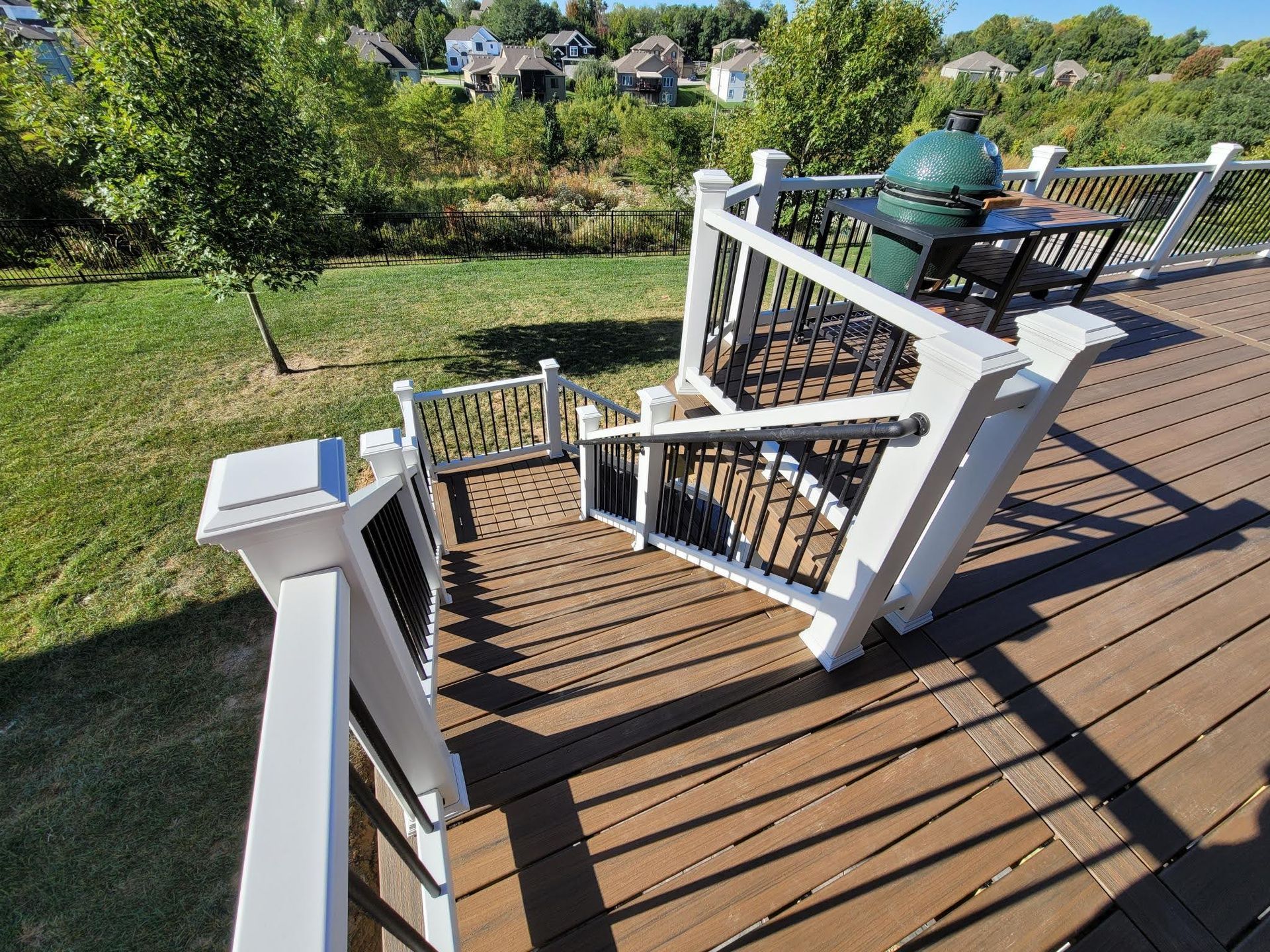 A wooden deck with stairs and a grill on it.